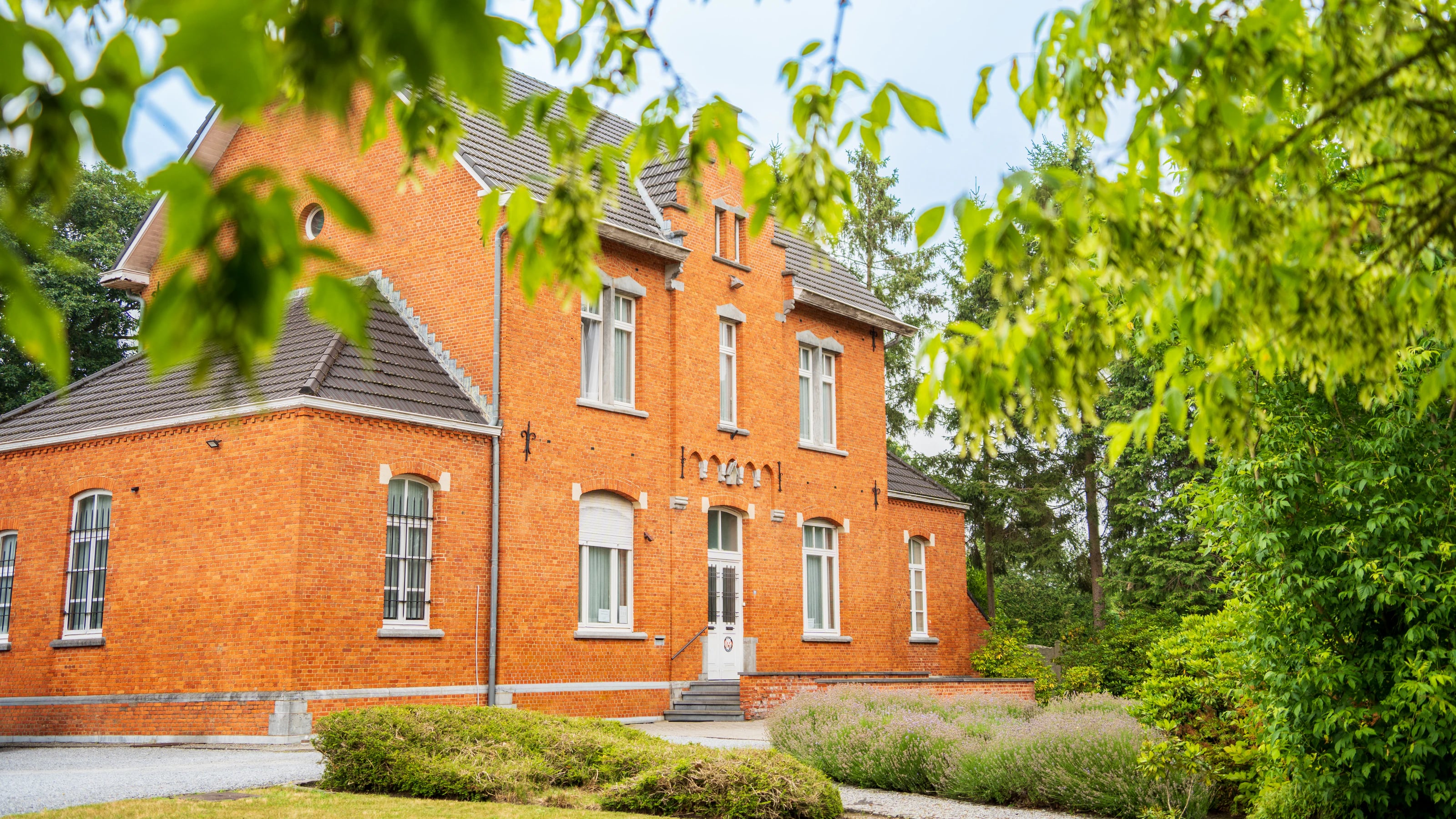 Het bakstenen praktijkgebouw van De Heerbaan aan Heerbaan 201 in Beringen, tussen het groen